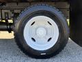 A close-up of a white wheel and tire from a 2017 Freightliner M2 106 featuring a five-stud hub design and rugged tire tread