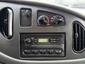 Dashboard of a 2006 Ford Econoline featuring climate control knobs and a radio with AM FM options and a digital clock display