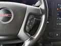 Close-up of a 2023 GMC Savana steering wheel featuring the GMC logo and controls for audio and cruise settings.