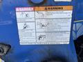 A warning label on a blue New Holland T4050 tractor detailing safety precautions and hazards associated with operating the machinery