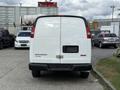 A white 2018 GMC Savana cargo van with a bare rear door showing the vehicle's branding and emblem