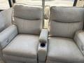 Two plush recliner seats with armrests and a central cup holder in between them designed for comfort in a recreational vehicle