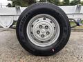 A close-up of a silver wheel with a black tire labeled Roadian GTC and a pink sticker on the side, part of a 2023 RAM Promaster 3500 van