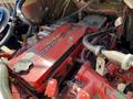 Close-up of a red Cummins engine cover with visible hoses and wiring in a Freightliner B2 engine compartment