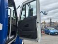 A blue 2013 International DuraStar 4300 truck with its driver's side door open showcasing the interior features and controls inside the cabin