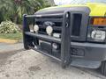 A 2010 Ford F-550 Super Duty with a black grille guard featuring two front lights and a winch mounted near the center