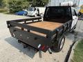 A 2020 Ford F-350 SD with a flatbed design featuring a wooden surface and black metal frame with rear lights and a towing hitch