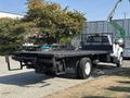A 2018 Ford F-750 flatbed truck with a black bed and a grid-like safety barrier at the rear parked in a lot