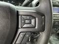 Close-up of the steering wheel controls in a 2018 Ford F-150 featuring volume and media buttons