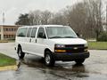 A white 2021 Chevrolet Express van with a three-row design featuring black bumpers and chrome accents parked on a wet surface