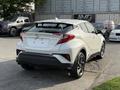 A 2021 Toyota C-HR in white is shown from the rear angle with a sporty design and sleek lines highlighting its modern features and shape