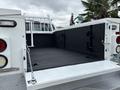 A 2013 Ford F-250 SD truck bed with a black rubber lining and a tailgate secured with chains