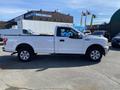 A white 2018 Ford F-150 truck with a standard cab and bed, featuring chrome wheels and a toolbox in the truck bed
