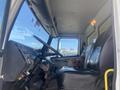 Interior of a 1997 Freightliner FL70 featuring a driver's seat, steering wheel, and dashboard with various controls and instruments