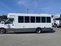 A white 2020 Chevrolet Express bus with large windows and a gray stripe along the bottom side of the vehicle
