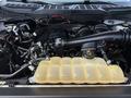 A 2021 Ford F-150 engine with a visible air intake and a yellow coolant reservoir in the foreground