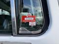 A close-up of a vehicle window showing a red certificate of approval sticker with dates for July and August and a number labeled GL 60779