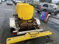 A yellow tank mounted on a silver and yellow 2014 Express 8 Foot Trailer with visible hoses and fittings attached to a metal frame