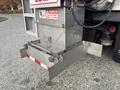 A metal snow plow attachment mounted on a 2013 Freightliner 114SD truck with warning signs for safety and operation