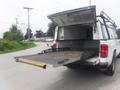 A 2015 Chevrolet Silverado 1500 with an open truck bed and a sliding tray extended out for loading or unloading cargo