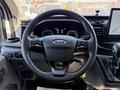 Steering wheel of a 2022 Ford Transit featuring controls for audio and cruise settings along with the Ford logo on the center airbag cover