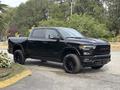 A black 2021 RAM 1500 pickup truck is parked with a sleek design and oversized black wheels