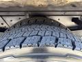 Close-up of a rugged tire with deep treads showcasing wear patterns mounted on a vehicle axle