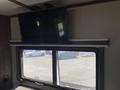 A flat-screen television mounted above a window in a recreational vehicle interior