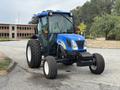 A blue and black 2009 New Holland T4020 tractor with large rear tires and a compact front design parked on a roadway