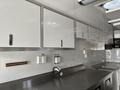 Interior of a 2020 Freightliner MT45 featuring metallic surfaces counter space and white cabinetry with handles