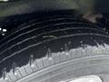 Close-up of a tire from a 2013 Ford E-350 showcasing the tread pattern with a small piece of grass resting on it