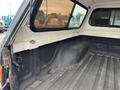 Interior of a 2004 Toyota Tacoma truck bed showing the floor and side walls with a clean finish and a small storage area in the corner