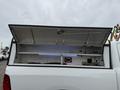 A 2016 RAM 1500 truck with an open bed cover revealing a storage area equipped with blue LED lights and various tools and equipment inside