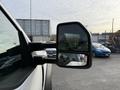 A 2020 Ford F-550 with a side mirror visible reflecting a person holding a camera and a compact car in the background