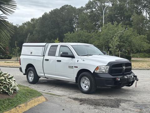 A white 2016 RAM 1500 truck with a cargo cap and front-mounted winch parked on a paved surface