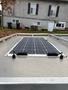 A solar panel is mounted on the roof of a vehicle with multiple black connection points visible on the edges of the panel