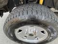 Close-up of a tire on a silver wheel with a rugged tread pattern designed for snowy conditions mounted on a 2014 Ford F-250 SD
