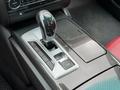 A close-up of the gear shift and control panel in a 2016 Maserati Ghibli featuring carbon fiber accents and a sleek silver design