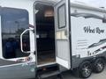 A 2013 Outdoor Wind River recreational vehicle with a partially open door and shiny wheels