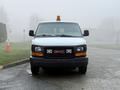A white 2016 GMC Savana van is parked with an orange beacon light on the roof facing forward