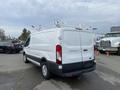 White 2017 Ford Transit van with cargo roof racks viewed from the rear angle
