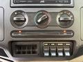 Dashboard controls of a 2010 Ford F-550 with climate control knobs audio system and switches for auxiliary functions