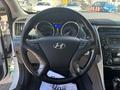 A 2014 Hyundai Sonata's steering wheel with control buttons and instrument panel displaying speed and fuel levels
