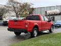 A red 2015 Ford F-150 pickup truck is parked with its rear facing the viewer showing its taillights and Ford emblem
