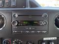 Dashboard of a 2013 Ford Econoline featuring a radio display with buttons for controlling audio functions and climate settings