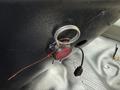 A red circular button labeled FIRE attached to a metal ring on a black surface with a small black connector cable nearby