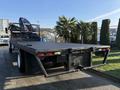 A 2015 Hino 358 flatbed truck with a textured black bed and visible red and white tail lights
