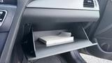 The glove compartment of a 2018 Hyundai Sonata containing a closed booklet resting on a flat shelf