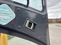 Close-up of a control panel on a 2017 John Deere 50G featuring a silver lever and a circular sticker detailing construction machinery information