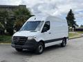A 2022 Mercedes-Benz Sprinter van in white with a high roof and black accents is parked on a paved surface